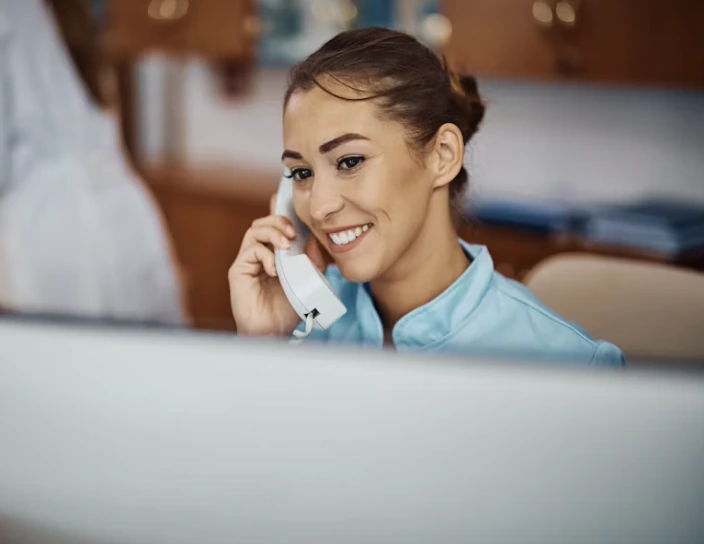 A nurse listening and smiling during a telephone conversation